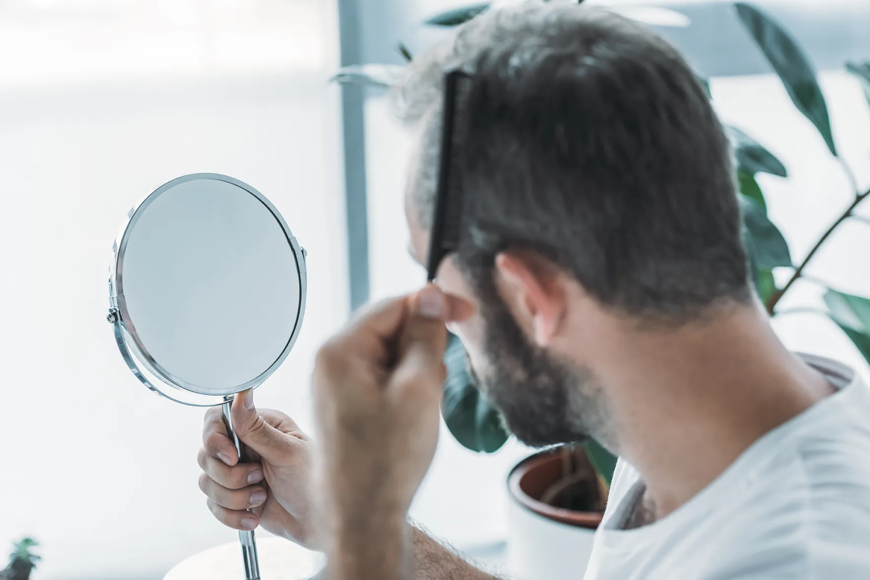 middle aged man combing hair and looking at mirror